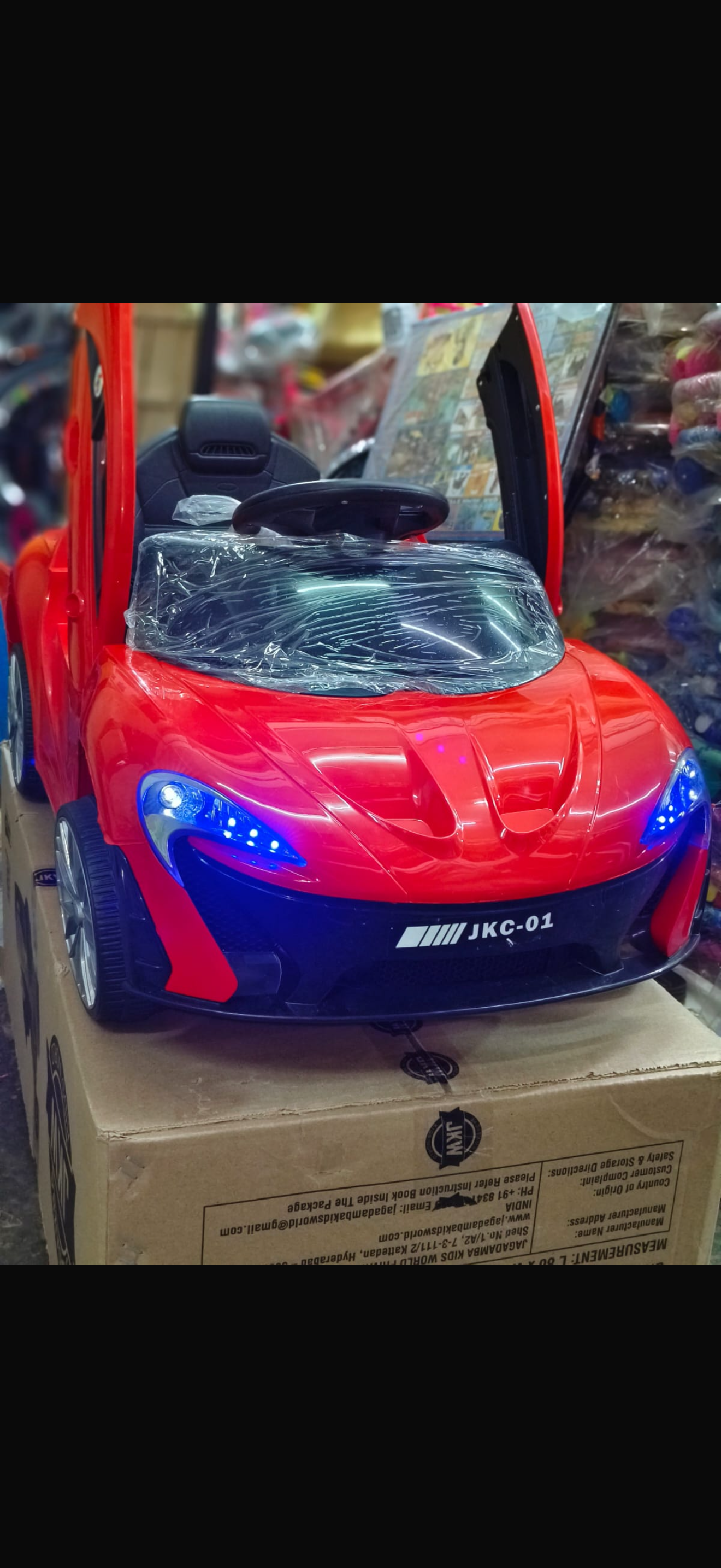 Red and blue toy car with working lights on a cardboard box
