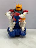 Toy figure with a yellow head and blue and red body on a white surface.