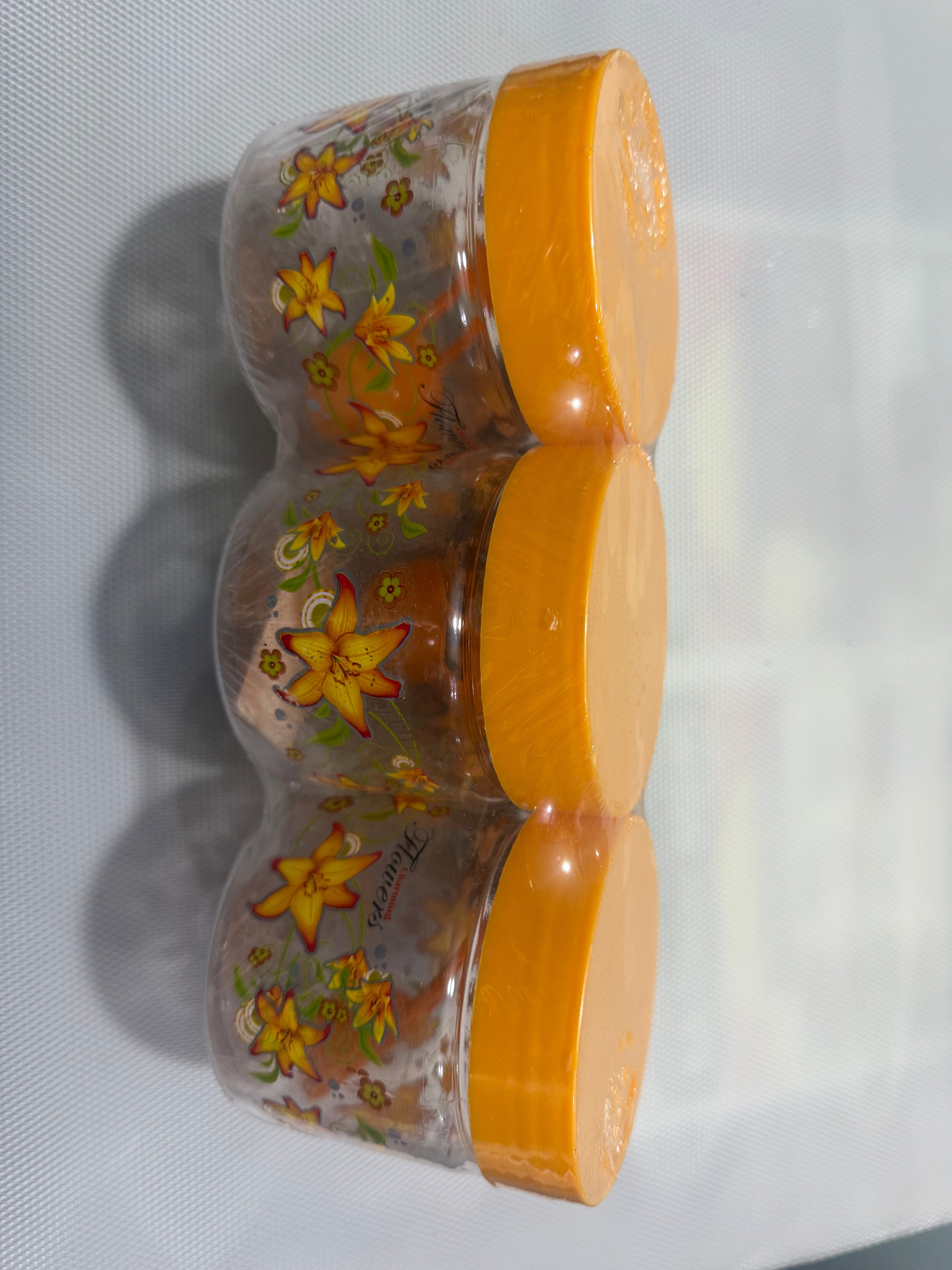 Three plastic jars with floral designs and orange lids 